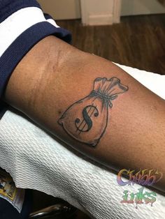 a man with a tattoo on his arm has a bag of money in the shape of a dollar sign