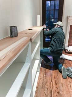 a man kneeling on the floor next to a shelf