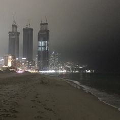 the city skyline is seen in the distance on a foggy night at the beach