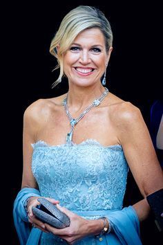 a woman in a blue dress is holding a cell phone and smiling at the camera