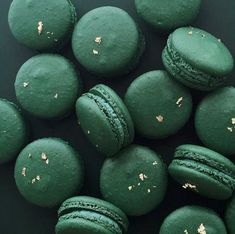 green macaroons with gold sprinkles on black background, top view