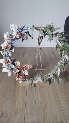 a wreath made out of paper flowers and greenery on a wooden floor with a string