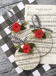 three red roses are placed on top of sheet music paper and tied together with ribbon