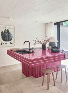 a kitchen with red counter tops and stools next to an island in the middle