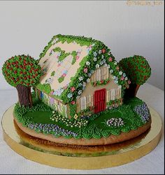 a cake that is shaped like a house with trees and bushes around it on top of a table