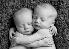 two newborn babies cuddle together in black and white