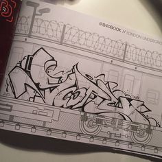 an open book with graffiti written on the pages and in front of it is a drawing of a train