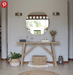 there is a mirror on the wall above a table with a basket and potted plant