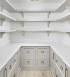 an empty room with white shelves and drawers