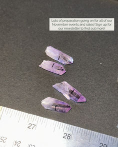 three amethysts sitting on top of a table next to a ruler