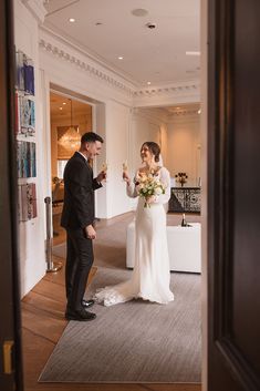 a bride and groom are standing in the doorway to their reception room, holding champagne flutes