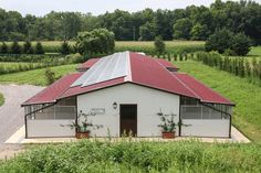 an aerial view of a barn with a solar panel on the roof, and green fields in the background