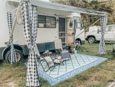 an rv is parked in the grass with two chairs and a table on top of it