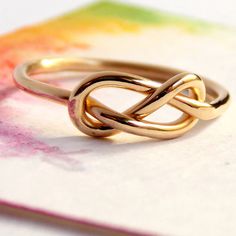 a gold ring sitting on top of a table next to a piece of colored paper