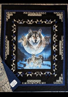 a quilt with three wolfs on it and the moon in the sky behind them