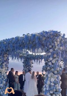 a bride and groom standing under an arch covered in blue hydrangeas at the end of their wedding ceremony