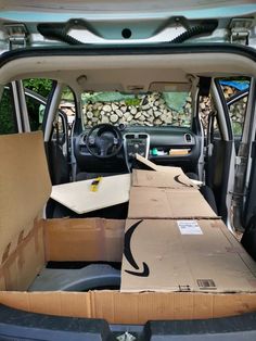 the back of a van with boxes in it's cargo area and another box on the floor