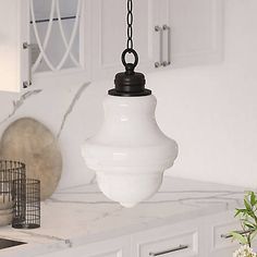 a white light hanging from the ceiling in a kitchen with cabinets and drawers behind it