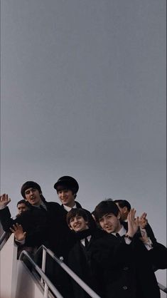 a group of men standing on top of a boat next to each other holding their hands in the air