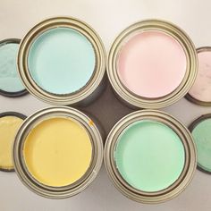 six different colors of paint in small tins