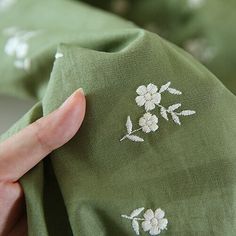 a hand is holding a green cloth with white flowers on it, and the fabric has been stitched together