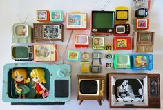 there are many old tvs and toys on the wall in front of each other