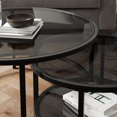 a glass table with some books and a bowl on it in a living room next to a couch