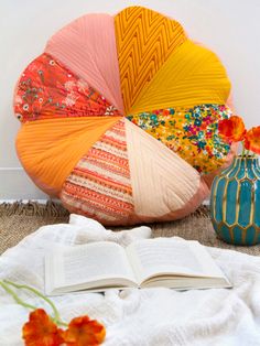 an open book is sitting on the floor next to some colorful pillows and vases