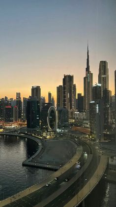 the city skyline is lit up at night, and there are many cars driving on the road