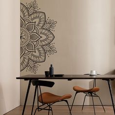 two chairs sitting at a table in front of a wall with a flower design on it