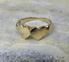 a gold ring with two hearts on it sitting on top of a stone slab,