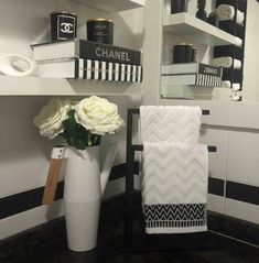 a bathroom with black and white decor, towels and flowers in a vase on the counter