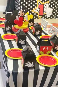 a mickey mouse party table with plates and napkins