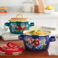 two colorful pots on a kitchen counter, one has a lid and the other has a spoon in it