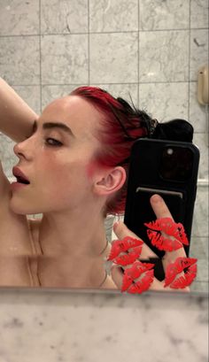 a woman with red hair taking a selfie in the mirror