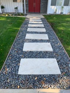 a stone path leading to a red door in front of a house