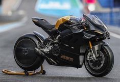 a black and gold motorcycle parked on the side of a race track with it's wheels down