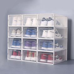 several clear bins with various pairs of shoes in them on a gray background,