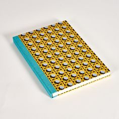 a yellow and blue dotted notebook on a white surface