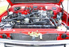 the engine compartment of an old red car with its hood up and it's hood down