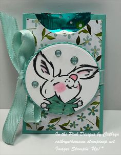 a card with an image of a rabbit on it's face and green ribbon