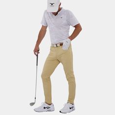 a man in a white shirt and khaki pants holding a golf club