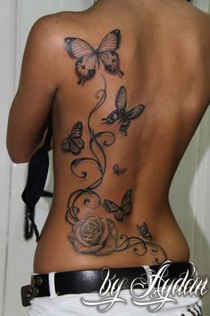 the back of a woman's body with butterflies and roses on it