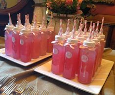 there are many bottles with straws in them on the table and one is filled with pink liquid