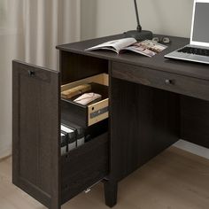 a laptop computer sitting on top of a wooden desk next to a drawer with files