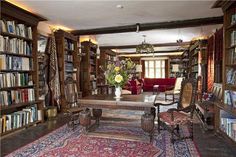 a room with lots of bookshelves and chairs in the center, along with a rug on the floor