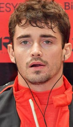 a close up of a person with ear buds in his ears and wearing an orange jacket