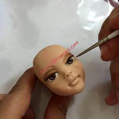 someone is painting the face of a doll