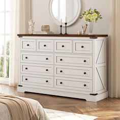 a white dresser with drawers and a mirror on it's side, in front of a window