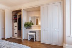 a bedroom with white closets and wooden flooring next to a large mirror on the wall